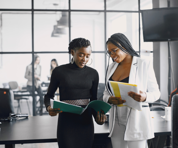 Business women talking near the desk during a coffee break in the hallway of the big corporation