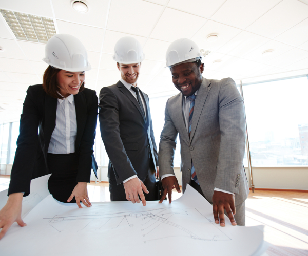 Confident architects in protective helmets looking at blueprint