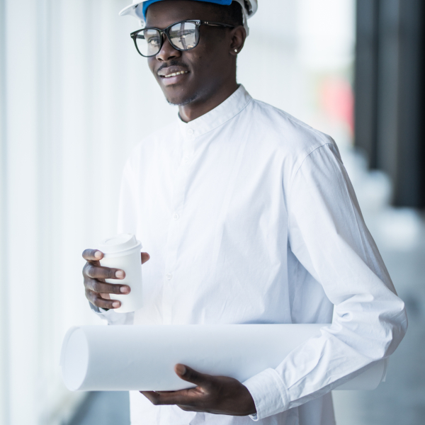 Young Afro-American engineer with blue prints in front of panoramic windows in office